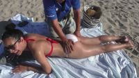 Guy Doing A Massage On A Girl On The Beach In A Bikini